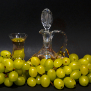 Stillleben mit grünen Weintrauben, die eine Glaskaraffe und ein Glas mit Grappa umgeben