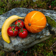Stillleben von Banane, Tomaten und Kürbis auf einem Stein drapiert