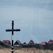 Schwarzes Kreuz mit Häusern im Hintergrund, Fotografie von Jörg Fiedler