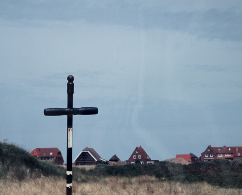 Schwarzes Kreuz mit Häusern im Hintergrund, Fotografie von Jörg Fiedler