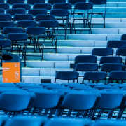 Das Foto zeigt Reihen von blauen Stühlen einer Open Air Veranstaltung. Den Akzent bildet ein Papierkorb mit einem orangefarbenen Aufkleber der BSR.