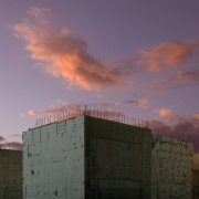 Betonrohbauten vor Wolken, die von der Abendsonne angestrahlt werden