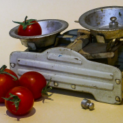 Das Foto im Querformat zweigt eine Waage mit zwei Waagschalen. In einer Waagschale liegt eine Tomate in der anderen ein Gewicht.