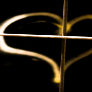 Das querformatige Foto zeigt ein auf schwarzem Untergrund gemaltes gelbes Herz, das von einer waagerechten und einer senkrechten Stange geteilt wird.