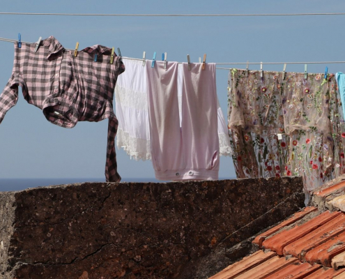 Frisch gewaschene Wäsche hängt unter blauem Himmel auf einer Leine.