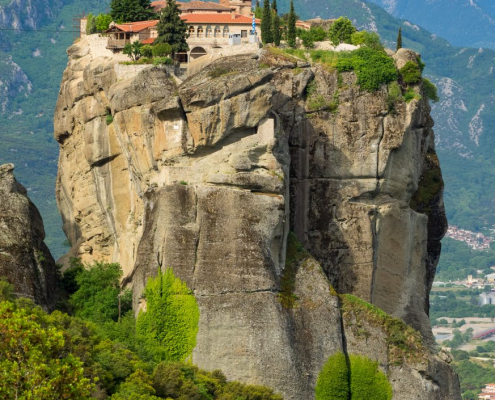 Das hochformatige Foto zeigt das Kloster Megalo Meteoro, das auf einem Felsen steht.