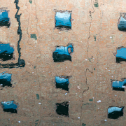 Das querformatige Foto zeigt das Spiegelbild eines Gebäudes mit quadratischen Fenstern in bewegtem Wasser.