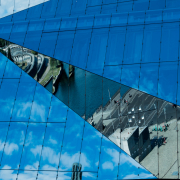 Das querformatige Foto zeigt den blauen Himmel, der sich im Cube spiegelt. Nur in einem dreieckförmigen Segment spiegelt sich der Washington Platz.