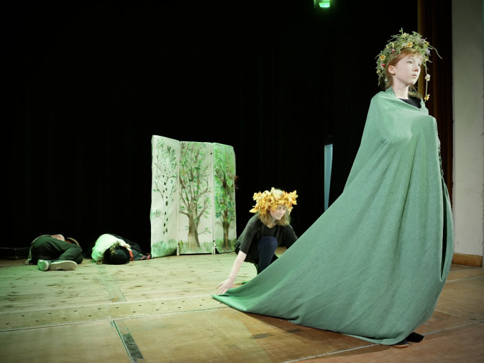 Theaterbühne mit vier Kindern, eine mit langen grünen Gewand