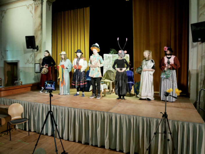 Theaterbühne mit sieben Kinder die bunte Kostüme tragen
