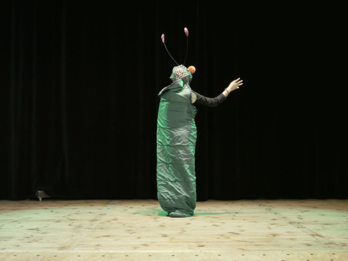 Ein Mädchen in eine Schmetterlingskokon Kostüm steht auf einer Theaterbühne