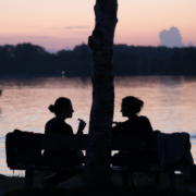 Auf dem hochformatigen Foto unterhalten sich 2 Frauen im Sonnenuntergang und Gegenlicht