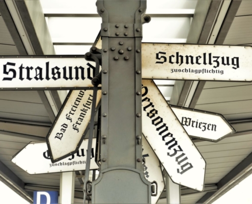 Das querformatige Bild zeigt auf einem Bahnhof alte schwarzweiss Schilder.