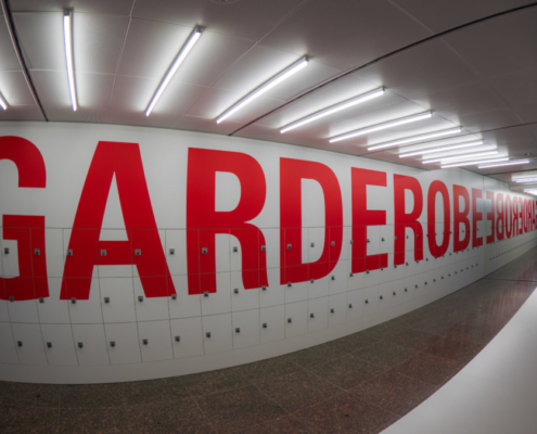 Das querformatige Bild zeigt die Schließfächer eines Theaters, auf denen in roten Buchstaben das Wort Garderobe steht.