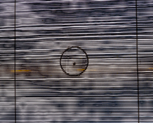 Das hochformatige Foto zeigt eine enge schwarze Raster mit orangefarbigen Flecken und einen Kreis in der Mitte