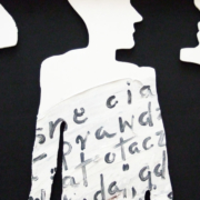 Das querformatige Bild zeigt den scherenschnittigen Umriss von Menschen mit einem in polnischer Sprache handgeschriebenen Zettel.