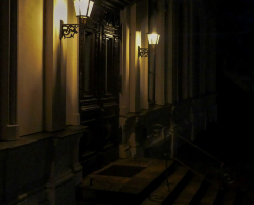 Das hochformatige Foto zeigt einen beleuchteten Hauseingang bei Nacht.