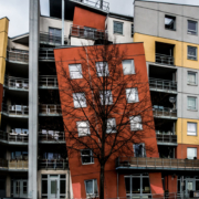 Das querformatige Foto zeigt einen Häuserblock, bei dem die Fassade eines Hauses schräg angebaut ist.