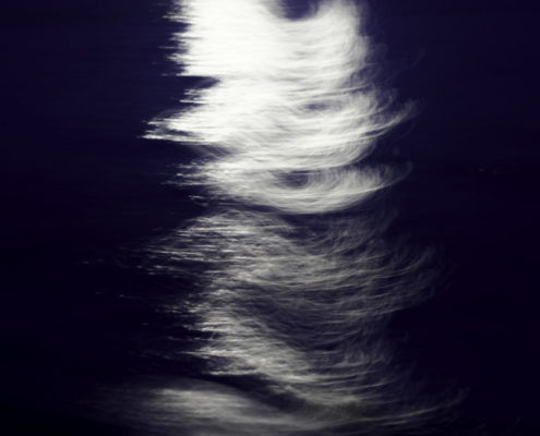 Das querformatige Foto zeigt eine Vollmondspiegelung im Meer mit bewegter Kamera aufgenommen.
