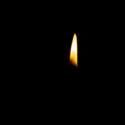 Das hochformatige ganz schwarze Foto zeigt nur die Flamme einer Kerze.