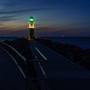 Das querformatige Foto zeit einen Blick auf einen Leuchtturm im Abendlicht.