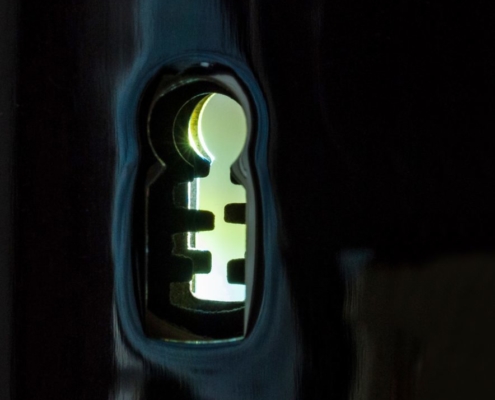 Das hochformatige Foto zeigt einen Blick durch ein Schlüsselloch in einem hellen Raum.