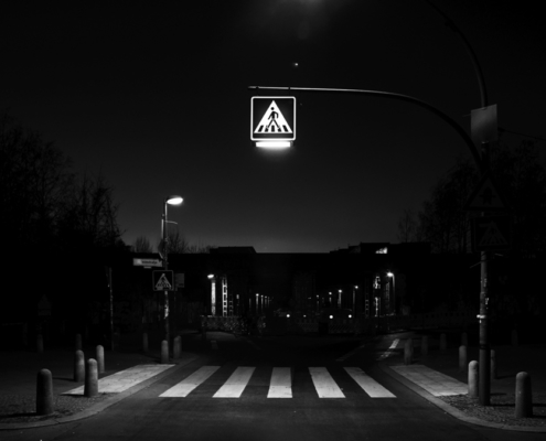 Das querformatige Foto zeigt die Straßenbeleuchtung über einem Zebrastreifen.
