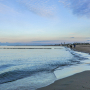 Das querformatige Foto zeigt den Strand der Ostsee bei Warnemünde mit einem Hotelhochhaus.