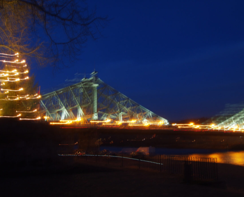 Das querformatige Foto zeigt eine beleuchtete Brücke und einen beleuchteten Weihnachtsbaum.