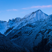 Das querformatige Foto zeigt einen Hochgebirgszug zur morgendlichen blauen Stunde.