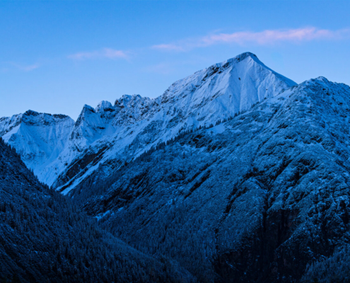 Das querformatige Foto zeigt einen Hochgebirgszug zur morgendlichen blauen Stunde.