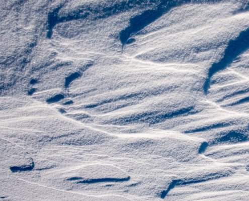 Das quadratische Bild zeigt eine monochrome Aufnahme einer Schneestruktur.