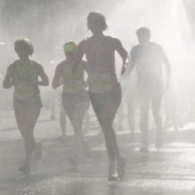 Das querformatige Foto zeigt Marathonläuferinnen und Läufer durch einen Wassersprühnebel.